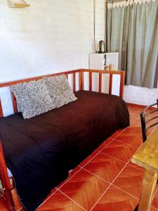 1 cama con edredón marrón en el suelo de madera en La Herradura, en Calingasta