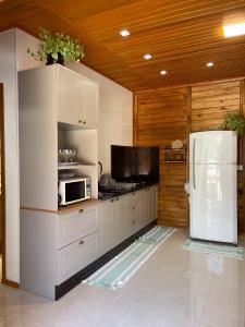 a kitchen with white cabinets and a white refrigerator at Recanto Praia das Vieiras in Porto Belo