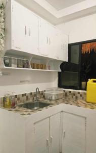 a kitchen with white cabinets and a sink at Duck and Drift Hostel - A sleeper Hostel in Puerto Princesa City
