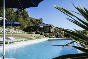 een zwembad met 2 stoelen en een parasol naast een huis bij Villa Casaliva with Private Pool in Albisano