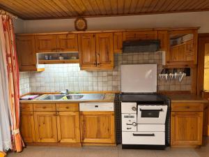 eine Küche mit Holzschränken und einem weißen Herd mit Backofen in der Unterkunft Ferienhaus Riegler in Trattenbach