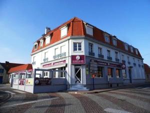 een groot wit gebouw op de hoek van een straat bij Les Carcahutes Le Duplex in Audresselles