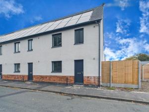 a white brick house with a fence on a street at Green Hat Stays Newport City in Newport