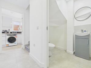 a bathroom with a toilet and a washing machine at Green Hat Stays Newport City in Newport