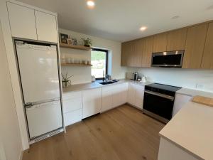een keuken met witte kasten en een zwarte koelkast bij 2BR, Views, Spacious, Luxury, New Home in Whistler +6 foto's