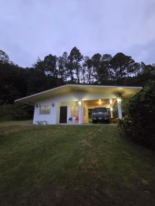 a small white house with a car parked in it at Los Senderos Amados in Bajo Boquete