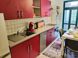 a kitchen with red cabinets and a sink at Lebensfreude in Markkleeberg