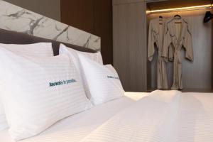 een slaapkamer met een bed met witte kussens en een jurk die er hangt bij Awwa Boutique Hotel in Canggu