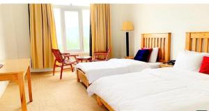 ein Hotelzimmer mit zwei Betten und einem Schreibtisch in der Unterkunft Mosavi Brother in Skardu