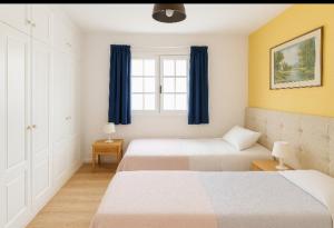 a bedroom with two beds and a window with blue curtains at Loma Estrella Ocean Suite Upper Arguineguín in Arguineguín