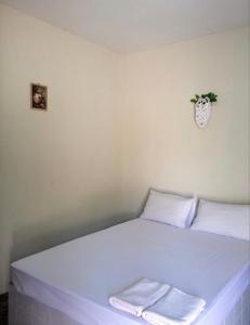 een wit bed in een kamer met een plant aan de muur bij คันทรี รีสอร์ท 