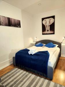 Dali 3 Ultra Central Stavanger City في ستافانغر: غرفة نوم بها سرير بملاءات زرقاء وفيل على الحائط