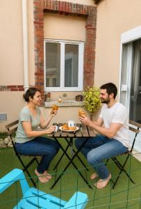 Ein Mann und eine Frau sitzen an einem Tisch und essen in der Unterkunft Le CoEuR du ViGnObLe Capacité 16 personnes max Venez partager un moment agréable en famille amis couples jeux Pétanque jacuzzi in Épernay