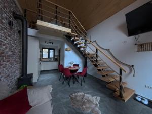 ein Wohnzimmer mit einer Treppe und einem Tisch und Stühlen in der Unterkunft Kolibe Doftana in Trăisteni