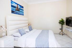 a white bedroom with a bed and a tv at Muyenga guestroom in Kampala