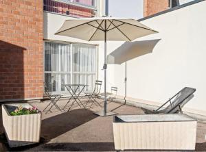 een patio met een tafel, een parasol en stoelen bij La petite boucane in Fécamp