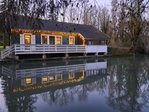 une maison sur l'eau avec des lumières dessus dans l'établissement Le rêve au fil de l'eau, à Marmagne 4 autres photos