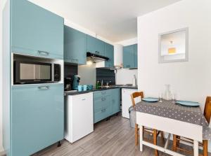 een keuken met blauwe kasten en een tafel met stoelen bij La petite boucane in Fécamp