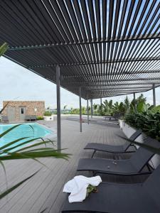 acovered deck with lounge chairs and a swimming pool at East Legon Loxwood House Condo with Gym & Pool in Accra