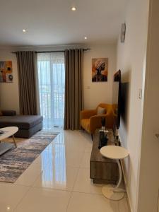 a living room with a couch and a tv at East Legon Loxwood House Condo with Gym & Pool in Accra