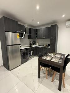 a kitchen with a table and a stainless steel refrigerator at East Legon Loxwood House Condo with Gym & Pool in Accra
