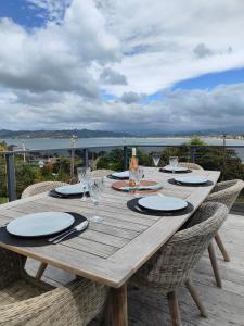 une table en bois avec des assiettes et des verres sur une terrasse dans l'établissement Hillside Haven, à Whitianga