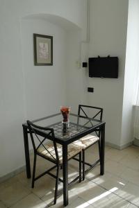 a glass table with two chairs and a television on a wall at lecasedimarco2 in La Spezia