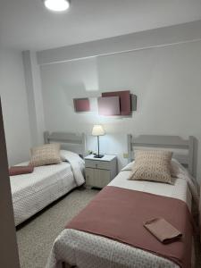 Un dormitorio con dos camas y una lámpara sobre una mesa. en Arcos Sol, en Puerto Naos