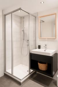 a bathroom with a glass shower and a sink at TinyAlps in Saalbach Hinterglemm