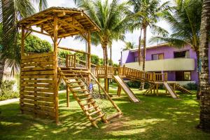 un parco giochi in legno in un cortile con palme di Resort Arcobaleno All Inclusive a Porto Seguro