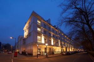 un gran edificio blanco en una calle por la noche en Caesar Hotel en Londres