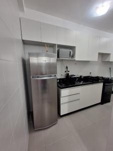 a kitchen with white cabinets and a stainless steel refrigerator at Cozy apartment near the airport in São José dos Pinhais