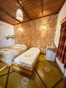 two beds in a room with a brick wall at Pousada Barra Nova Praiamar in Cascavel
