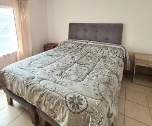 a bed in a bedroom with a blanket on it at Departamento bahia fonck in Puerto Montt