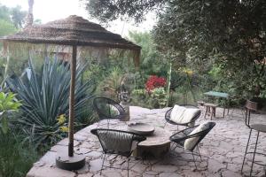 eine Terrasse mit Stühlen, einem Tisch und einem Sonnenschirm in der Unterkunft BIOtorisme-chama in Taroudant