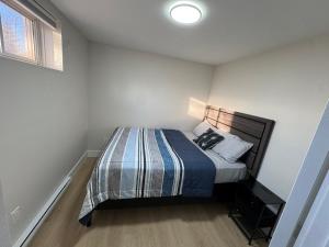 una piccola camera da letto con un letto con una coperta a righe di Cozy & Stylish Retreat with Modern Comforts a Moncton