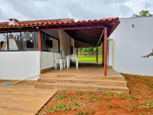 uma pérgola com uma mesa e cadeiras num deque em Chácara com piscina e lago aconchegantes em Planaltina