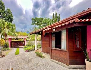 a small red building with a patio next to a house at Alfa Serra lago e montanha in Guapimirim