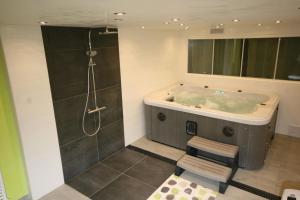 a bathroom with a tub with a shower and a stool at Le Chalet "Les Breuches" in Ramonchamp +25 photos