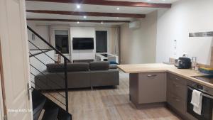 a kitchen and a living room with a couch and a staircase at Le duplex sigeannais in Sigean