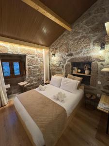 ein Schlafzimmer mit einem großen Bett und einer Steinwand in der Unterkunft Casas com Alma - O Palheiro - Gerês in Cabril