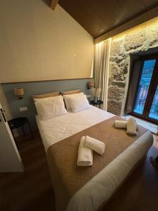 ein Schlafzimmer mit einem großen Bett, auf dem Handtücher liegen in der Unterkunft Casas com Alma - O Palheiro - Gerês in Cabril + 20 Fotos