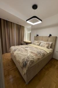 a bedroom with a large bed and a large light at Apartman La Campanella 2 in Vrnjci