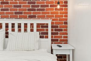 una camera da letto con un letto bianco e un muro di mattoni di The Brick Loft 1BR Calea Victoriei a Bucarest