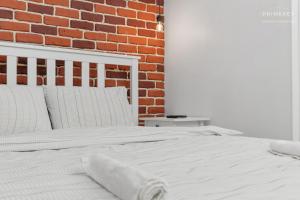 un letto bianco davanti a un muro di mattoni di The Brick Loft 1BR Calea Victoriei a Bucarest