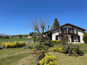 ein Haus mit Balkon und einem Garten mit Blumen in der Unterkunft Maison familiale Pays Basque in Ahaxe-Alciette-Bascassan