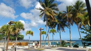 a group of people sitting on a bench next to the beach at Beau duplex T3 avec une superbe vue mer in Le Diamant