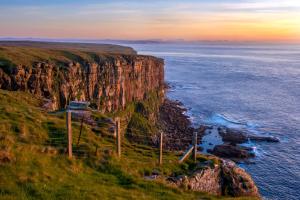 a view of a cliff near the ocean at sunset at Beyond North Cabins in Canisbay