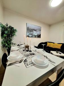 Dali 3 Ultra Central Stavanger City في ستافانغر: طاولة طعام مع أطباق بيضاء وشموع