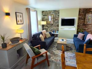 a living room with blue couches and a tv at The Wigtown Ploughman in Wigtown